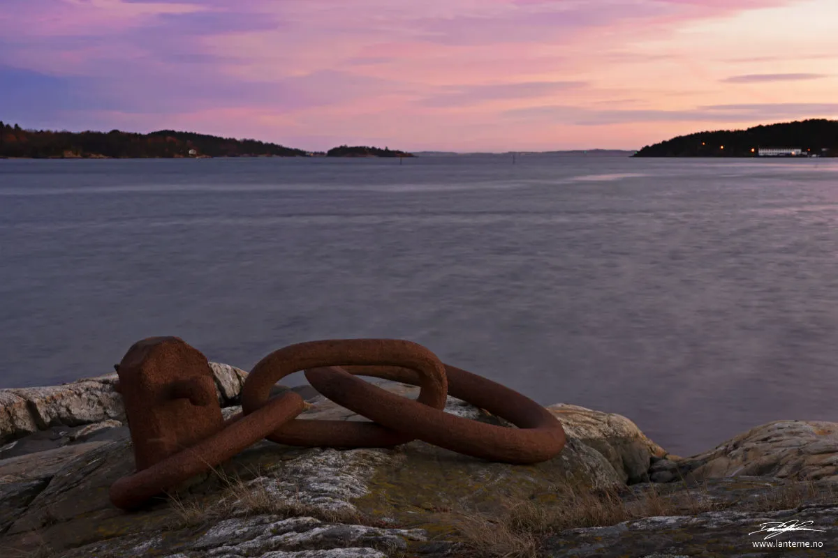 Rusten fortøyningsring på svaberg ved solnedgang over Sørlandet