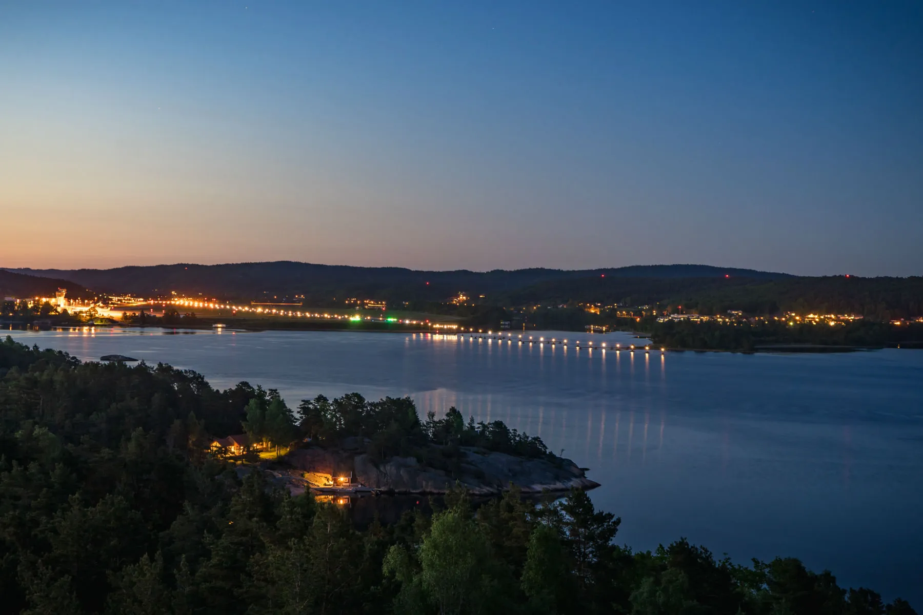 Blåtimen over Topdalsfjorden mot rullebanen og terminalen på Kjevik