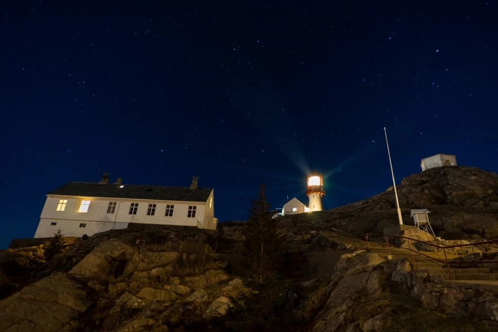 Lindesnes fyr og fyrvokterbolig under stjernehimmel på svaberget