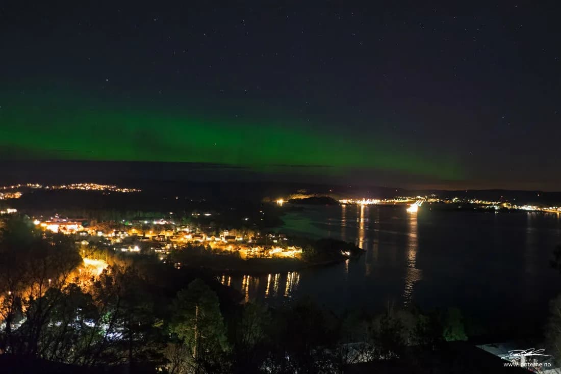 Grønn nordlysbue over Topdalsfjorden mot Kjevik sett fra Ålefjær