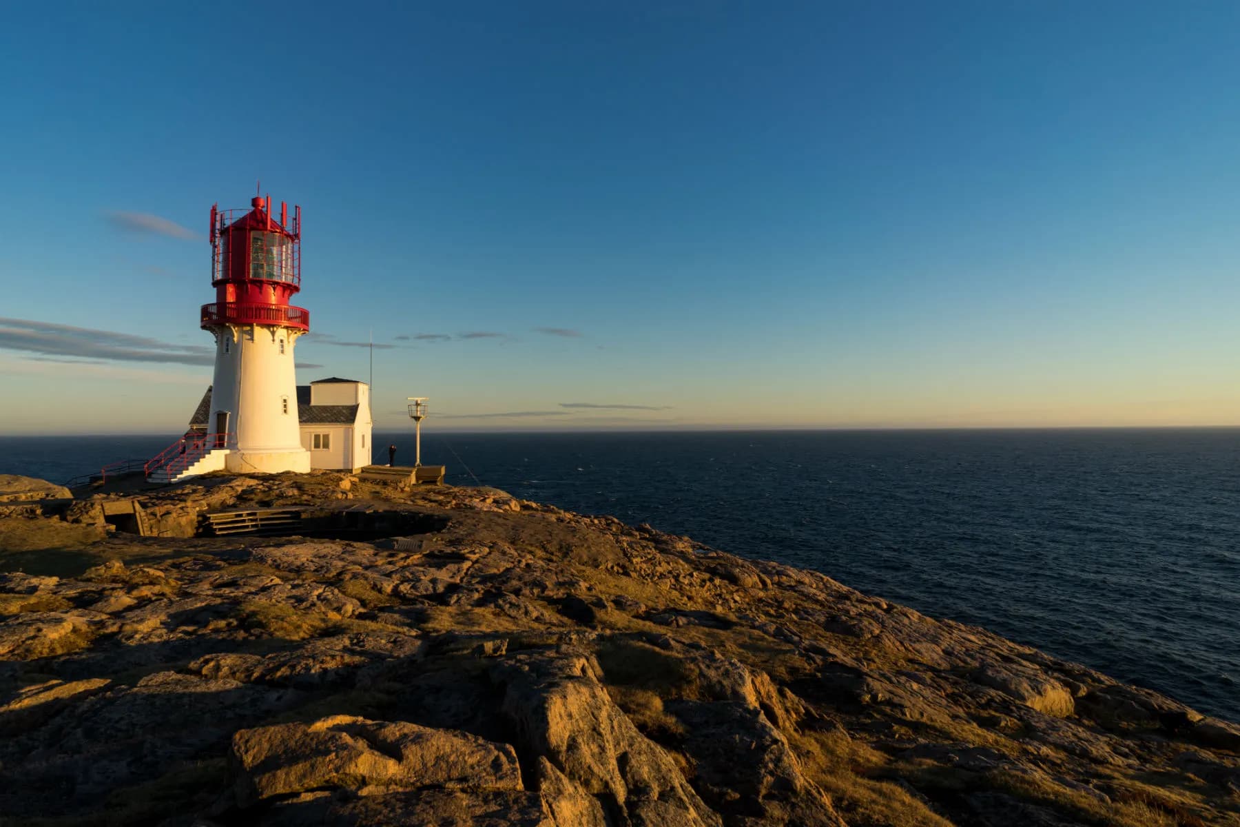 Lindesnes fyr på svaberg med åpent hav i kveldslys på sørspissen